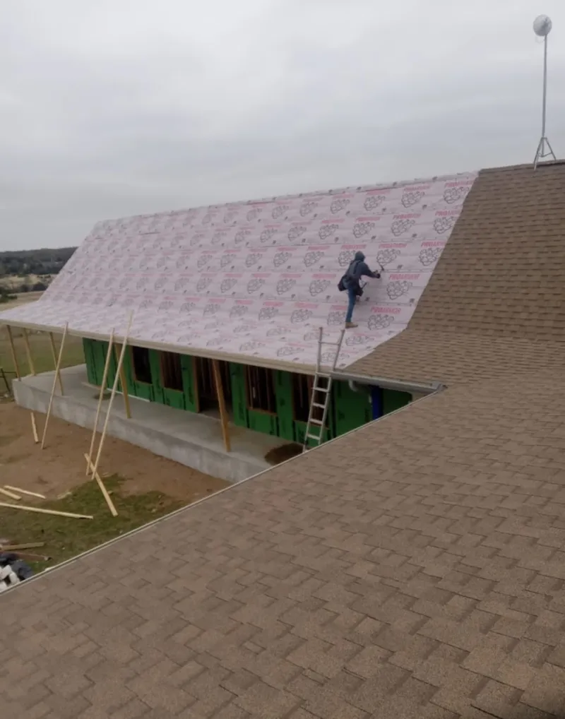Worker preparing underlayment for a metal roof installation in Cedartown